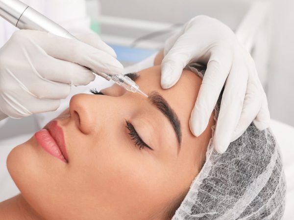 Young,Woman,Undergoing,Procedure,Of,Permanent,Eyebrow,Makeup,In,Tattoo